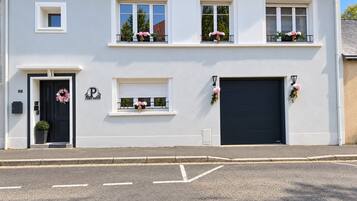 A two-story building with a black front door, a garage door, and multiple windows with flower boxes.