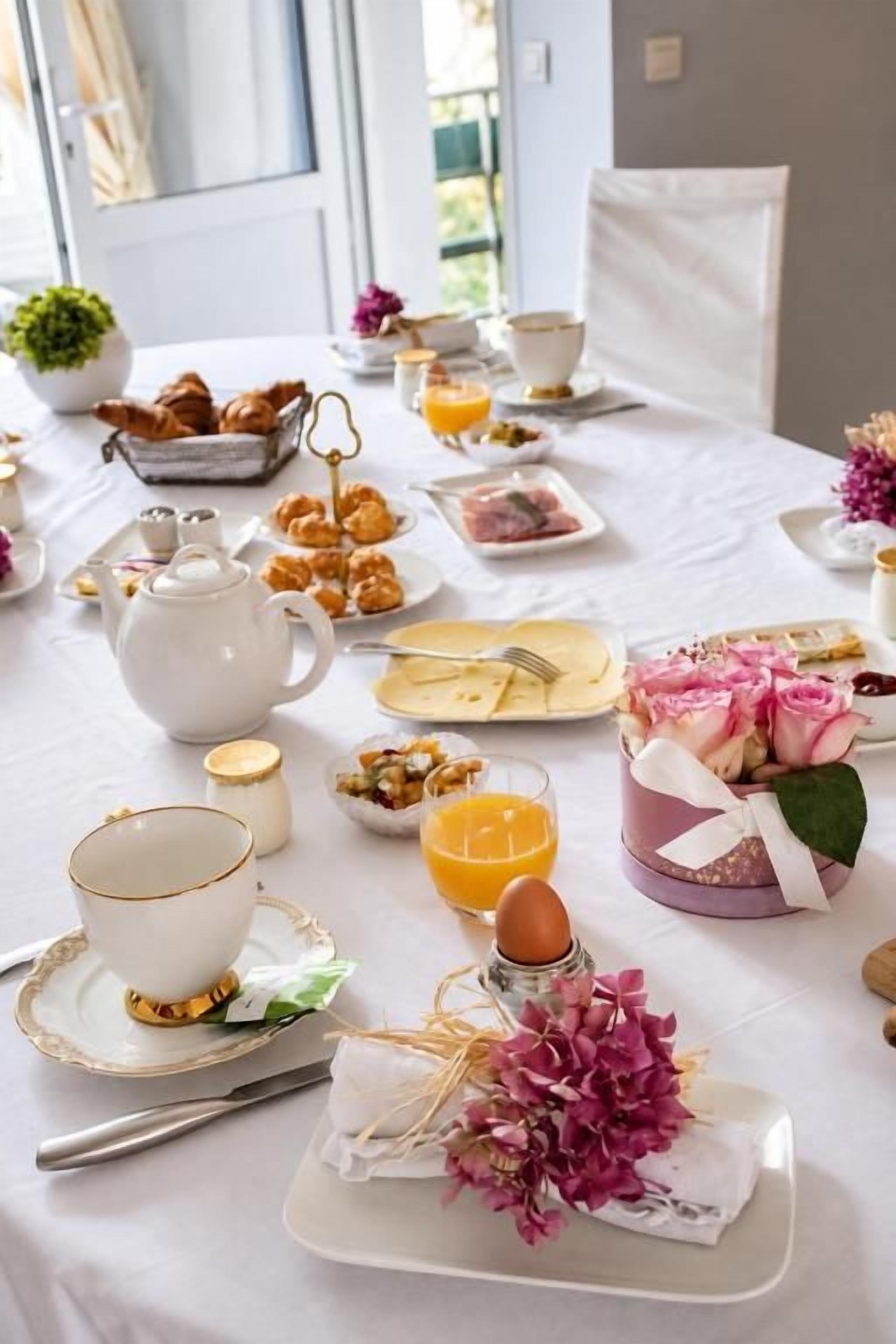 A breakfast table set with various food items, a teapot, and a cup.