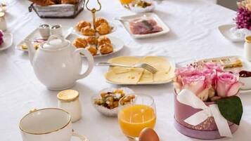 A breakfast table set with various food items, a teapot, and a cup.