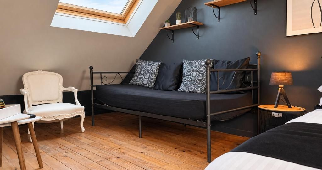 Habitación compacta con literas, una silla blanca, una mesita pequeña y un tragaluz.