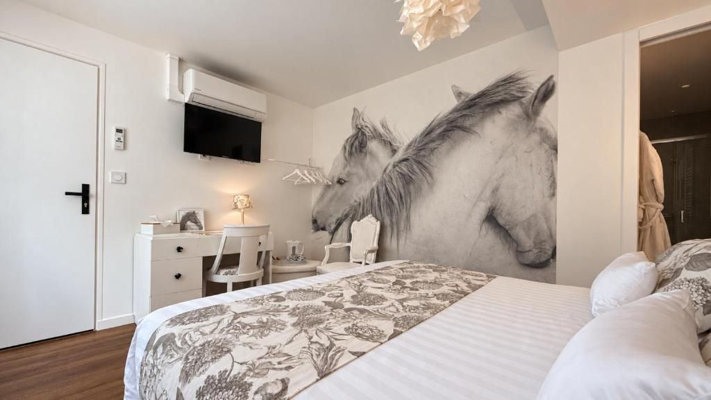 Una camera da letto con un letto grande, una scrivania, una sedia e una TV a muro.