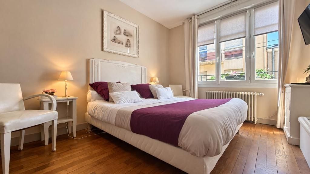 A bedroom with a bed, bedside tables, a chair, and a window with a view.