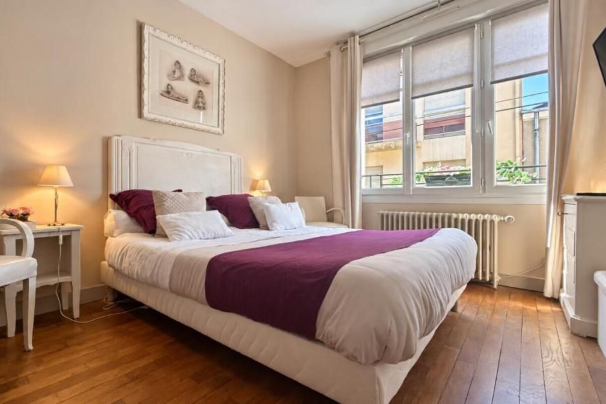 Une chambre à coucher avec un lit, des tables de chevet, une chaise et une fenêtre donnant sur un beau paysage.