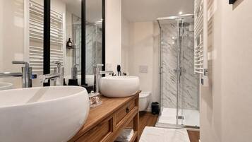 A modern bathroom with two sinks, a glass shower enclosure, and a wooden vanity.
