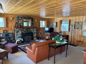 A cozy living room with a fireplace, leather sofa, and a television. - Rustic mountain cabin with lakeviews (South Lake Tahoe)