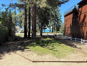 A fenced outdoor area with tall trees, a wooden building, and a view of the sea. - Rustic mountain cabin with lakeviews (South Lake Tahoe)
