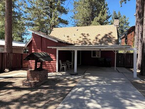 A covered outdoor area with a brick fireplace, a table and chairs, and a covered patio. - Rustic mountain cabin with lakeviews (South Lake Tahoe)