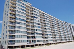 Ein mehrstöckiges Hotel mit Balkonen, einer glatten Fassade und blauem Himmel.