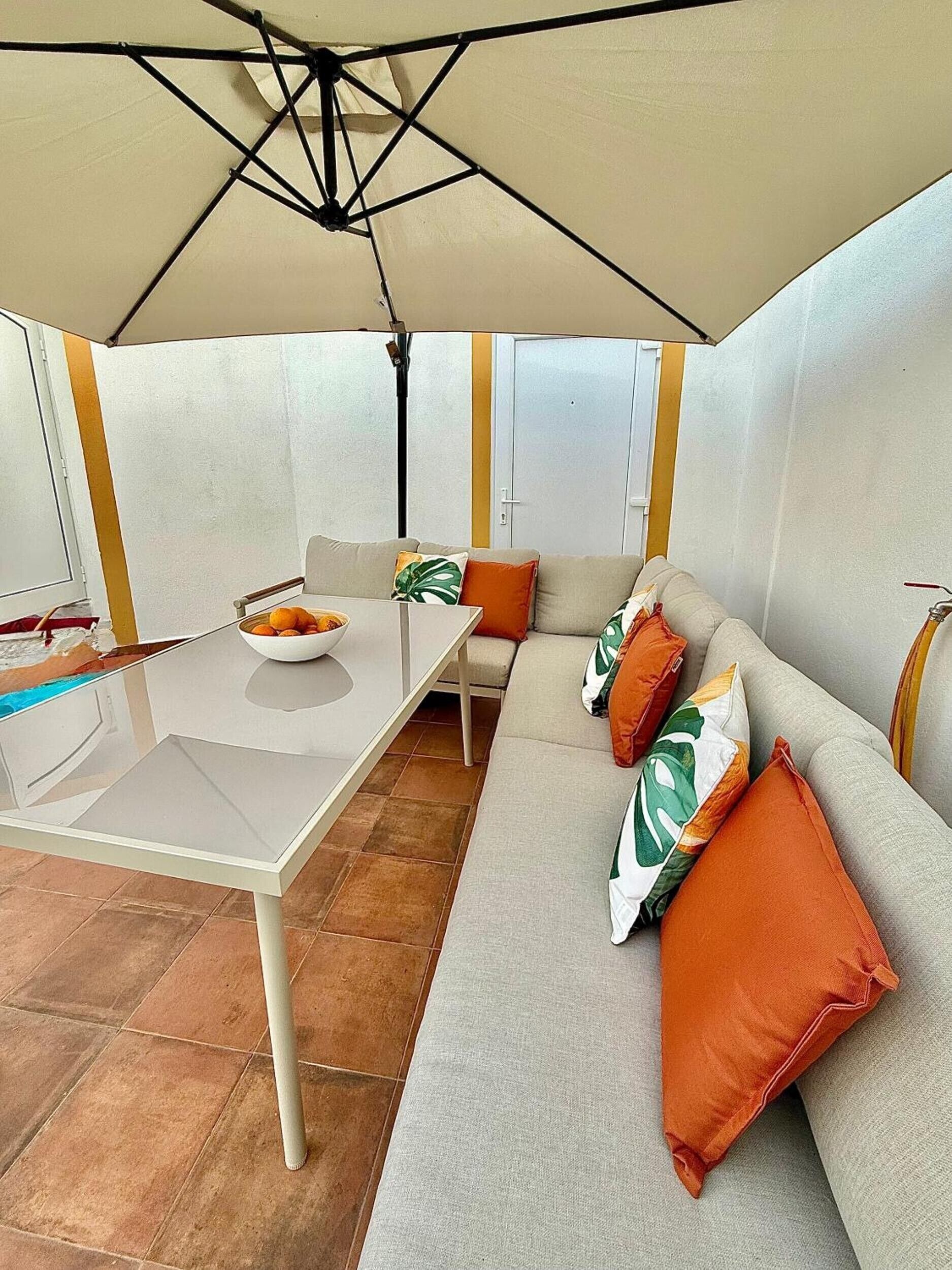 Un espacio al aire libre con mesa, sillas y sofá bajo una estructura tipo tienda.