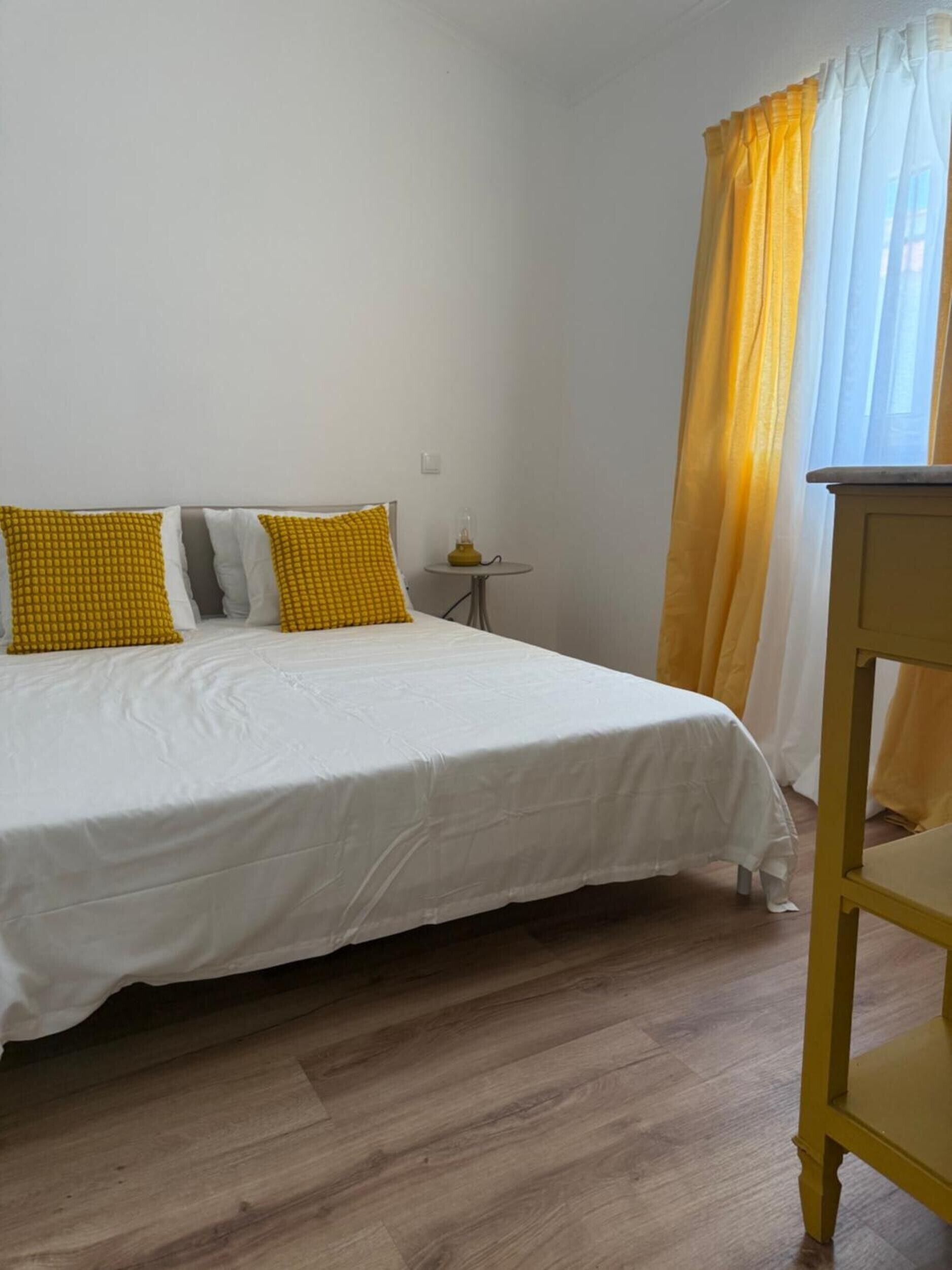 A bedroom with a bed, a small table, and a chair.