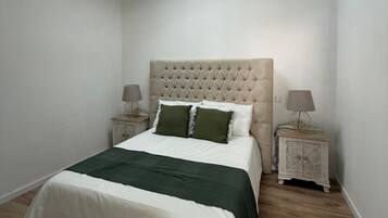 Un dormitorio con una cama, un tragaluz, dos mesitas de noche y una mesilla.