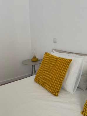 Una habitación de hotel con una cama, una mesita de noche con lámpara e interruptor de pared.