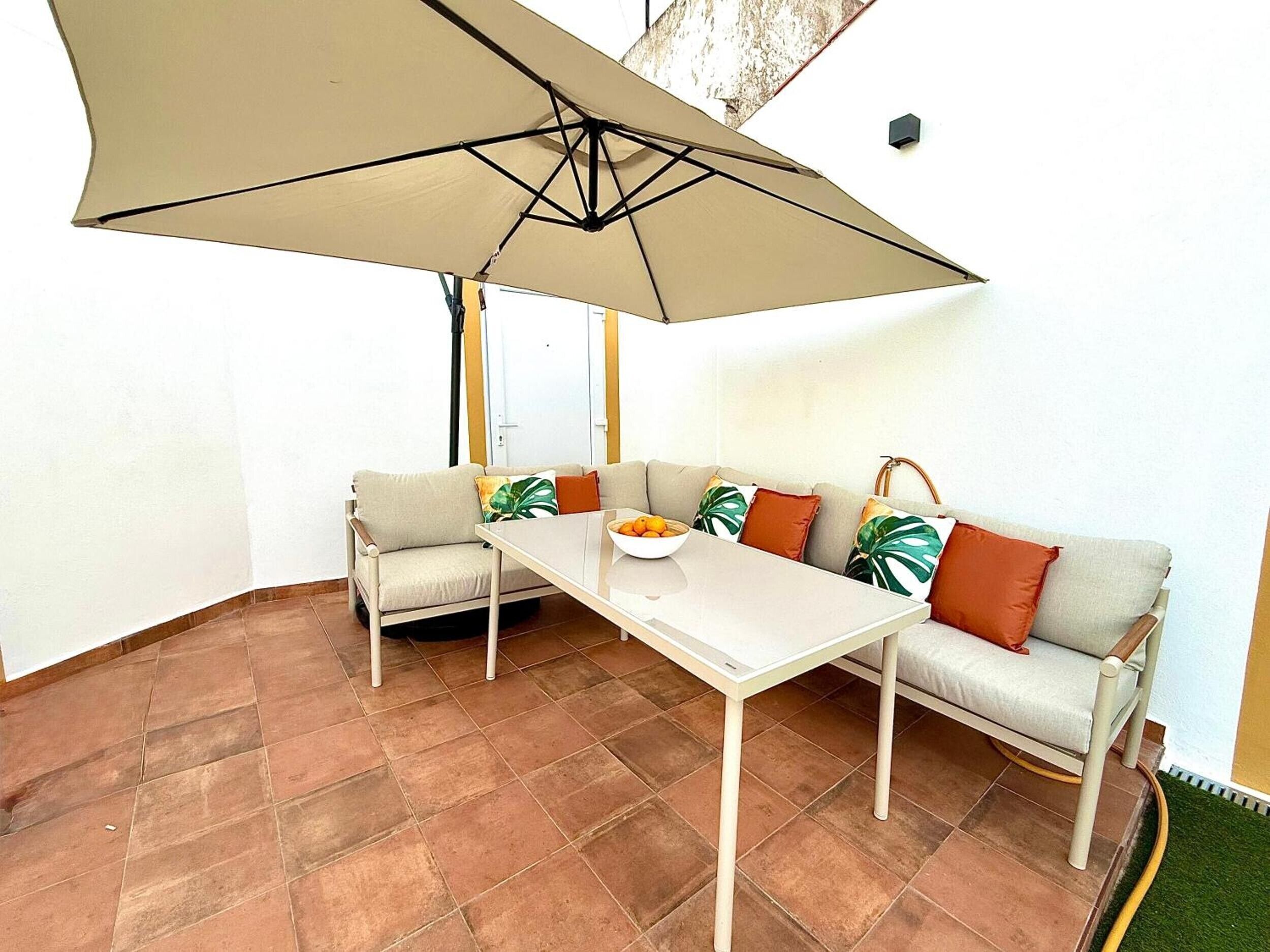 A corner seating area with a table, two sofas, and a large umbrella.