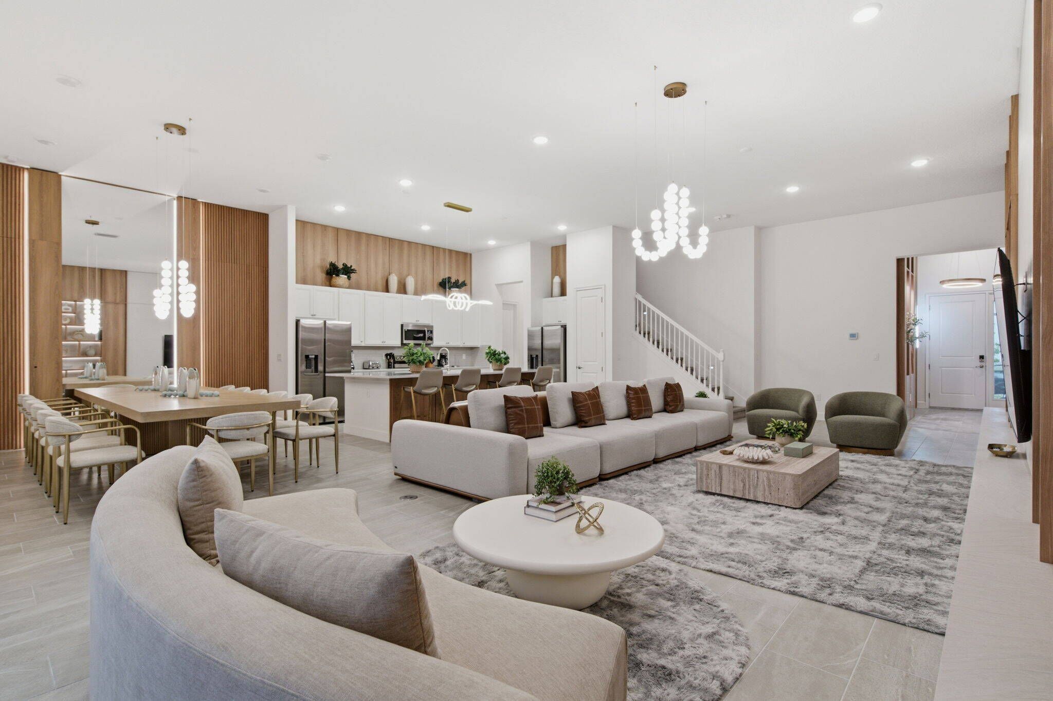 A modern living room with a sofa set, a dining area with a table and chairs, and a kitchen in the background.