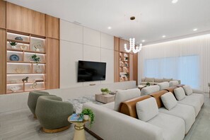 A modern living room with a sofa, a television, and a wooden shelving unit. - 15BR Your Best Vacation Starts Here (11037PG) (Orlando)