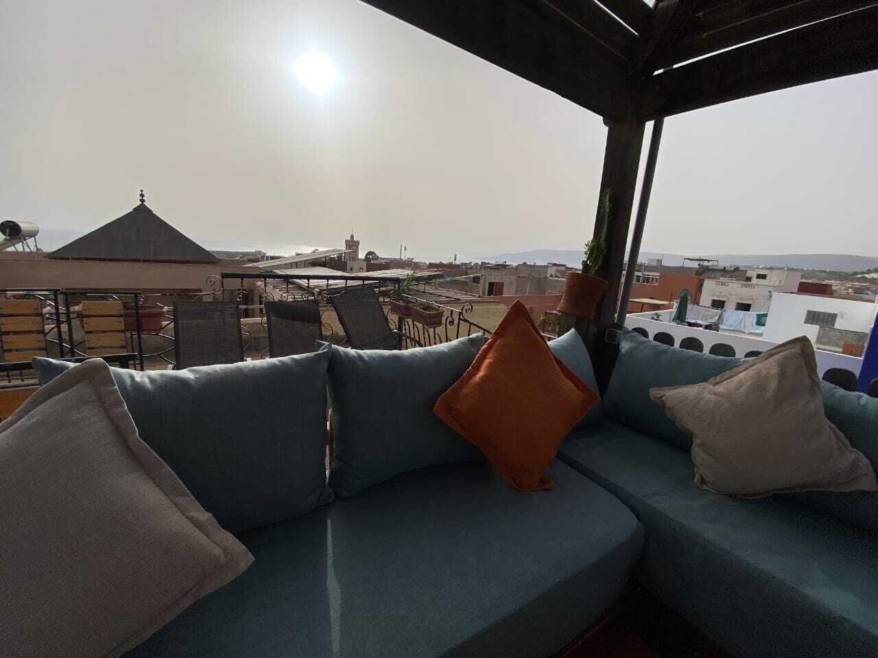 Área de estar no terraço com sofá e almofadas, com vista para a cidade.