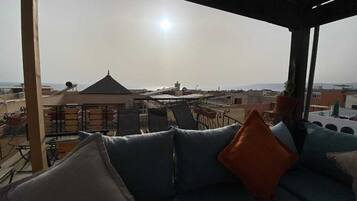 Une terrasse sur le toit, avec un canapé et des fauteuils, d’où l’on peut admirer la vue sur la ville.