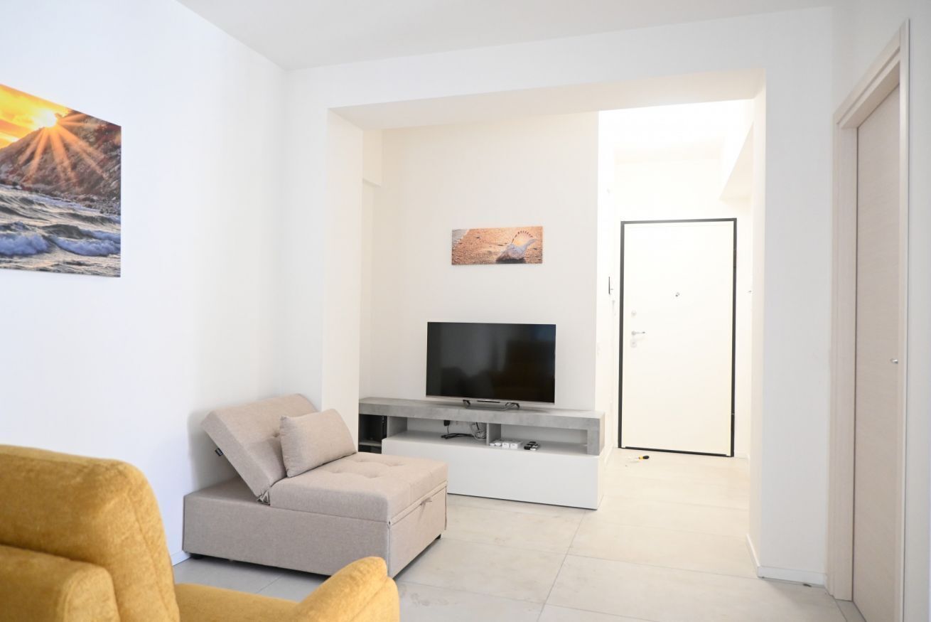 A modern living room with a sofa, a flat-screen TV, and artwork on the wall.