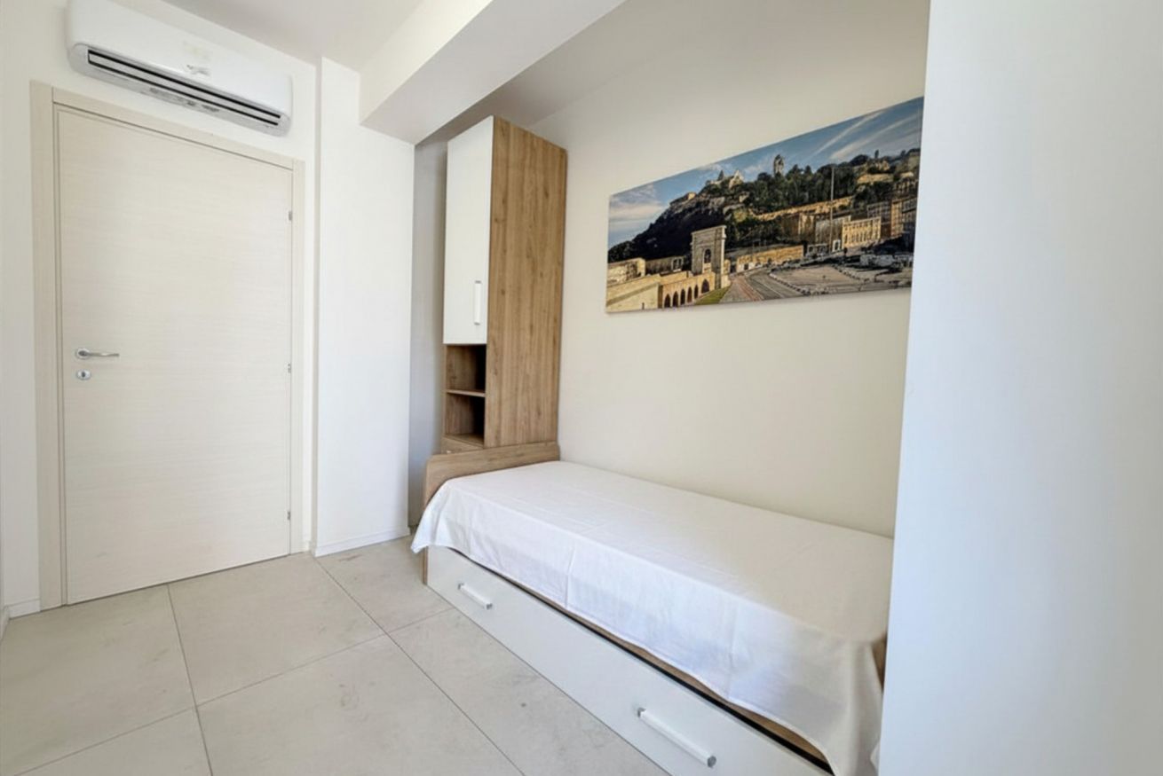 A bedroom with a bed, a wardrobe, a door, and a wall-mounted air conditioning unit.