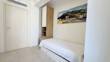 A bedroom with a bed, a wardrobe, a door, and a wall-mounted air conditioning unit.