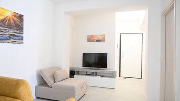 Una sala moderna con un sofá, un televisor de pantalla plana y obras de arte en la pared.