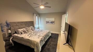 Ein Schlafzimmer mit einem Bett, einem Deckenventilator, einem Flachbildfernseher und einem Gemälde an der Wand.
