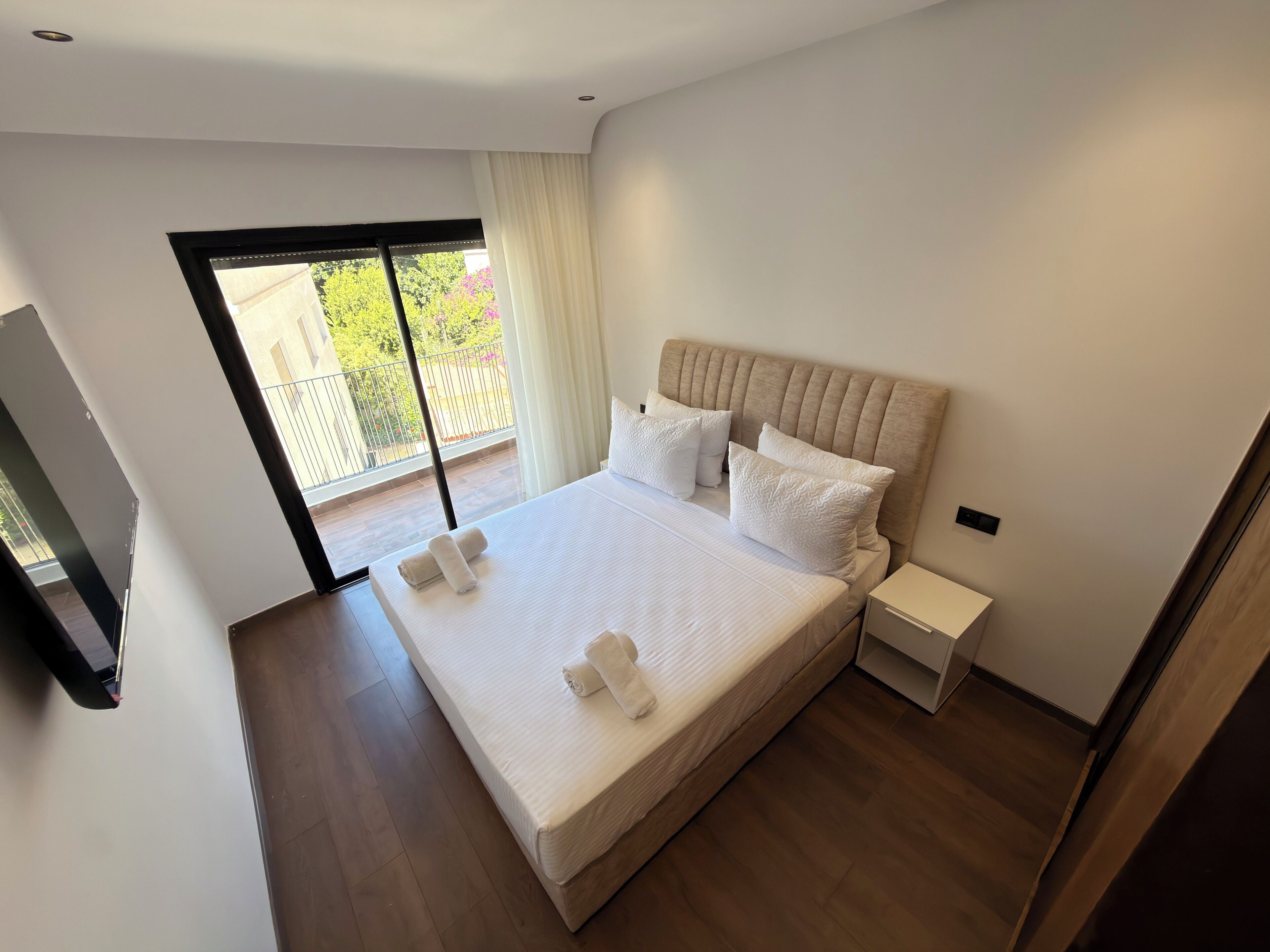 Un dormitorio moderno con una cama grande, una mesita de noche y un televisor.