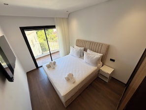 Un dormitorio moderno con una cama grande, una mesita de noche y un televisor.