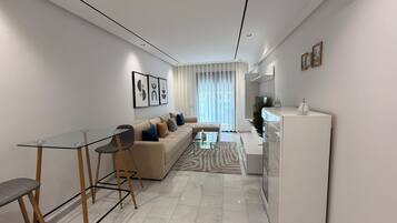 A modern living room with a glass dining table, a sofa, and a white cabinet.