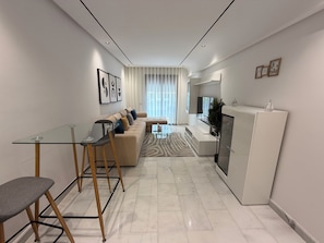 Una sala moderna con una mesa de vidrio, un sofá y un televisor.