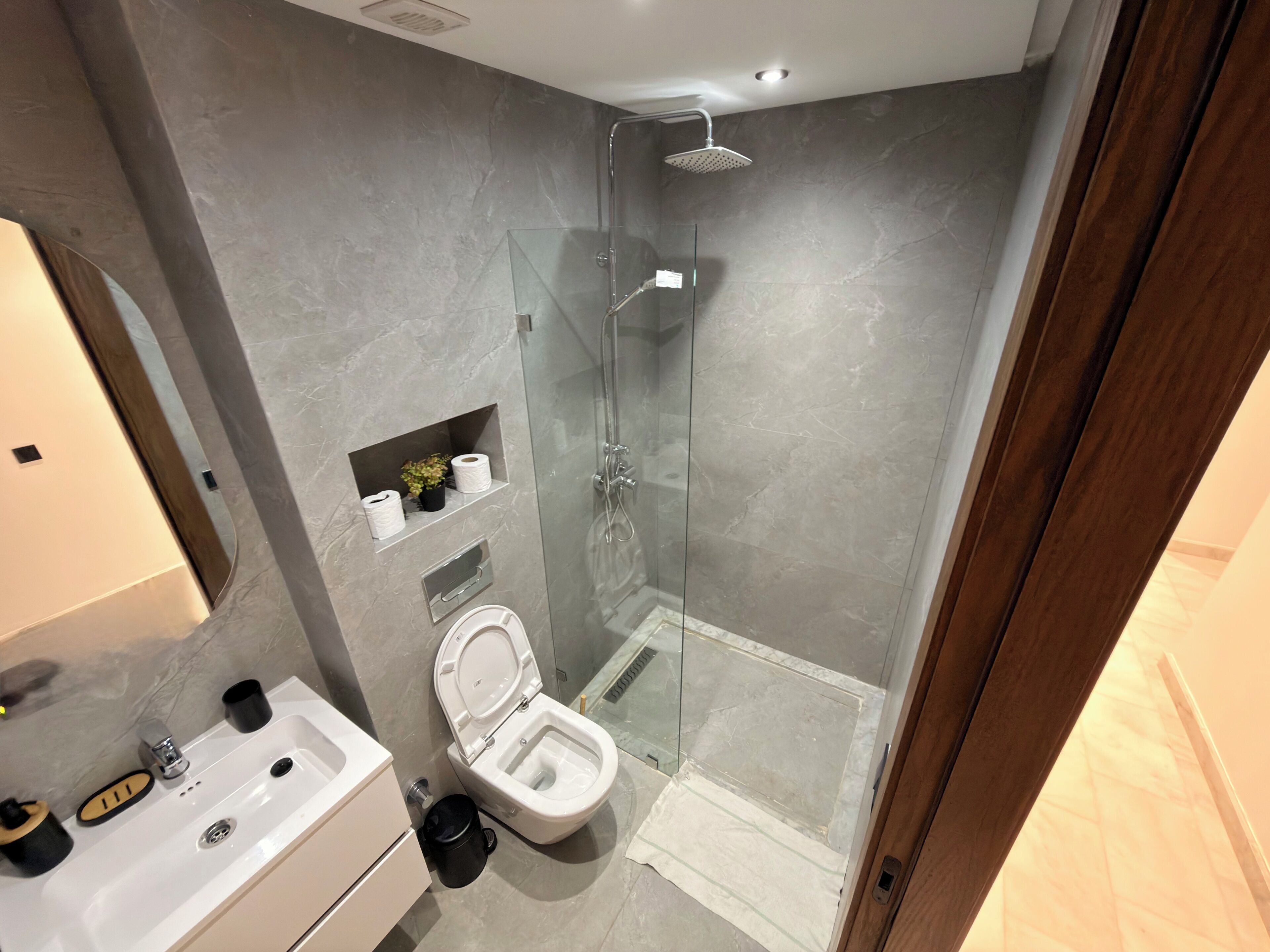 A modern bathroom with a glass-enclosed shower, a toilet, and a sink.