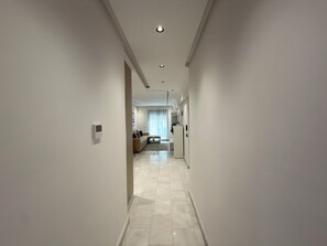 Un pasillo moderno de hotel con un conjunto de sofás, un refrigerador y un comedor a lo lejos.