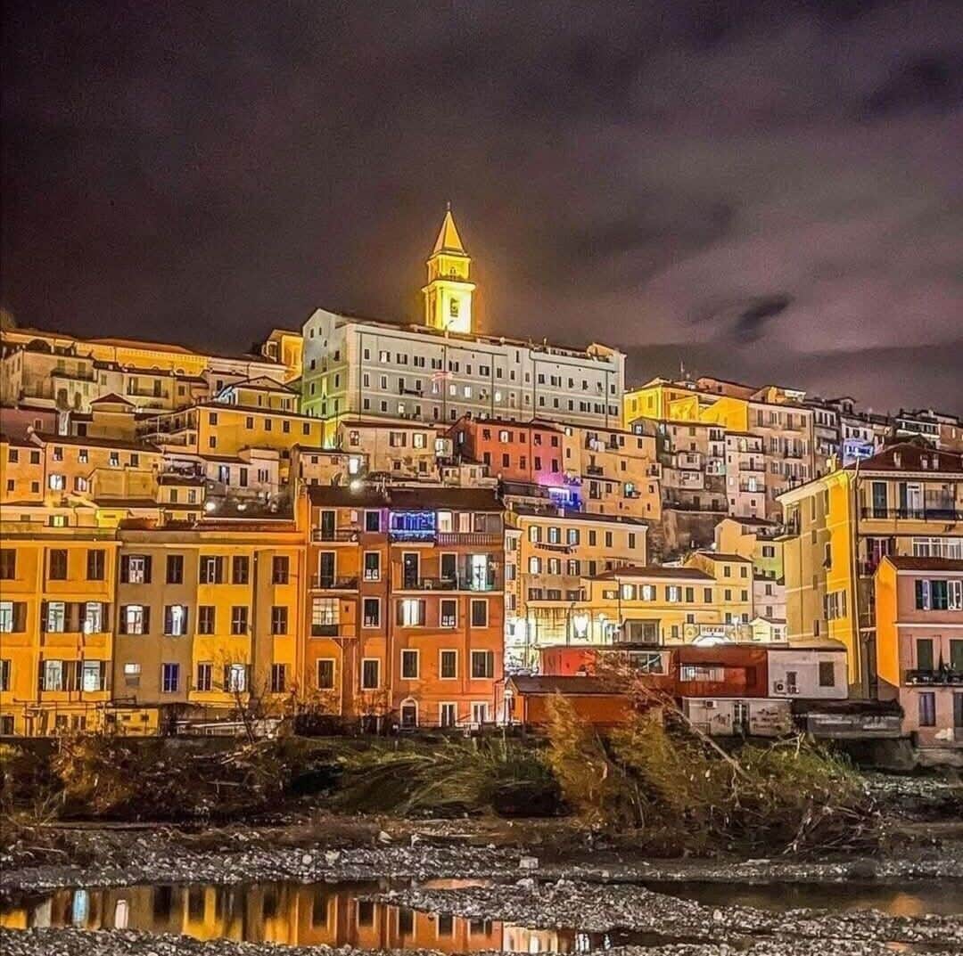 Vista nocturna de una zona urbana densamente poblada, con edificios muy cercanos al frente marítimo.