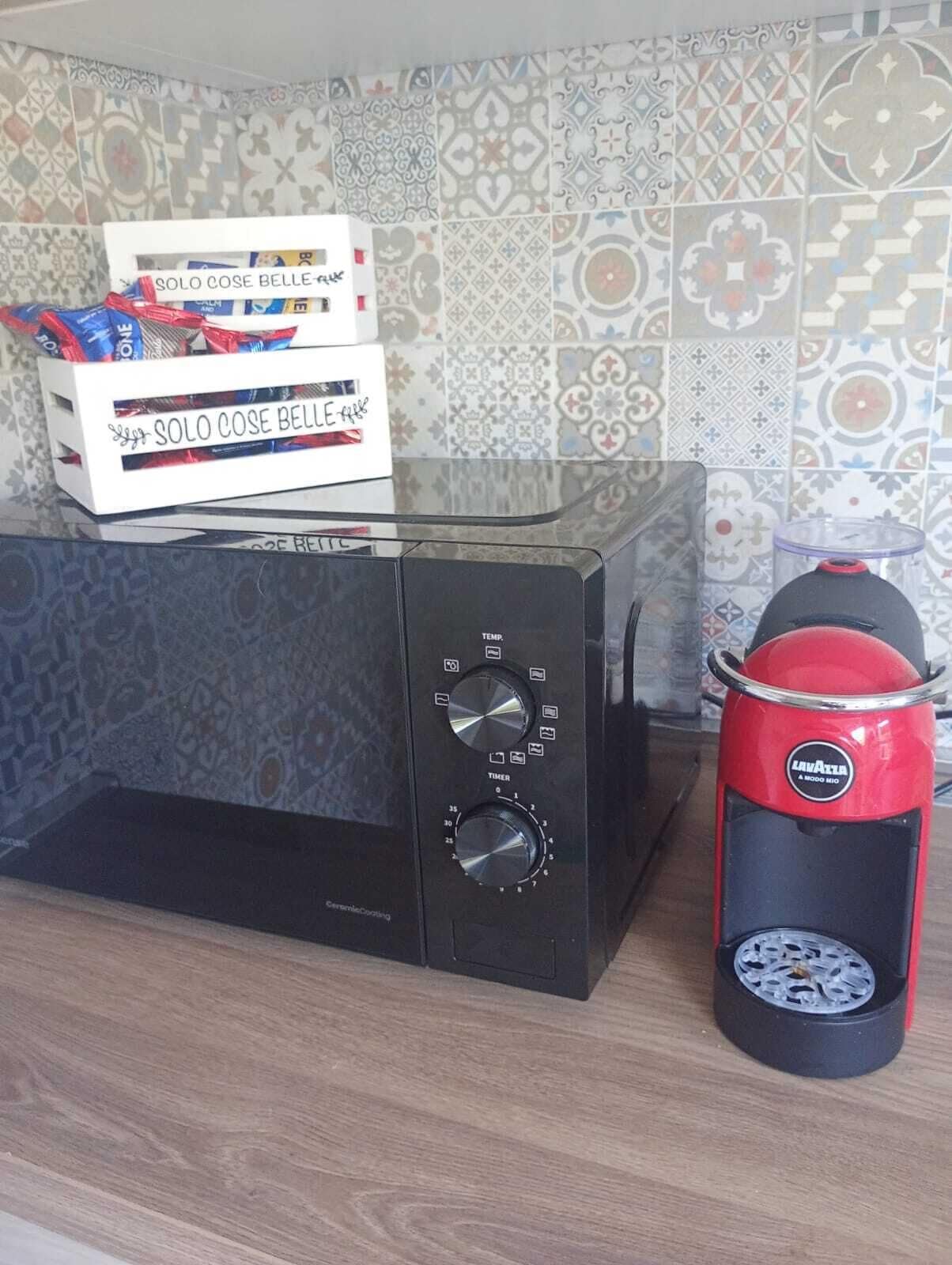 Eine Küche mit einer Mikrowelle, einer Kaffeemaschine und einer Packung Solo Cose Belle Kaffee.