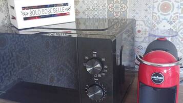 Eine Küche mit einer Mikrowelle, einer Kaffeemaschine und einer Packung Solo Cose Belle Kaffee.
