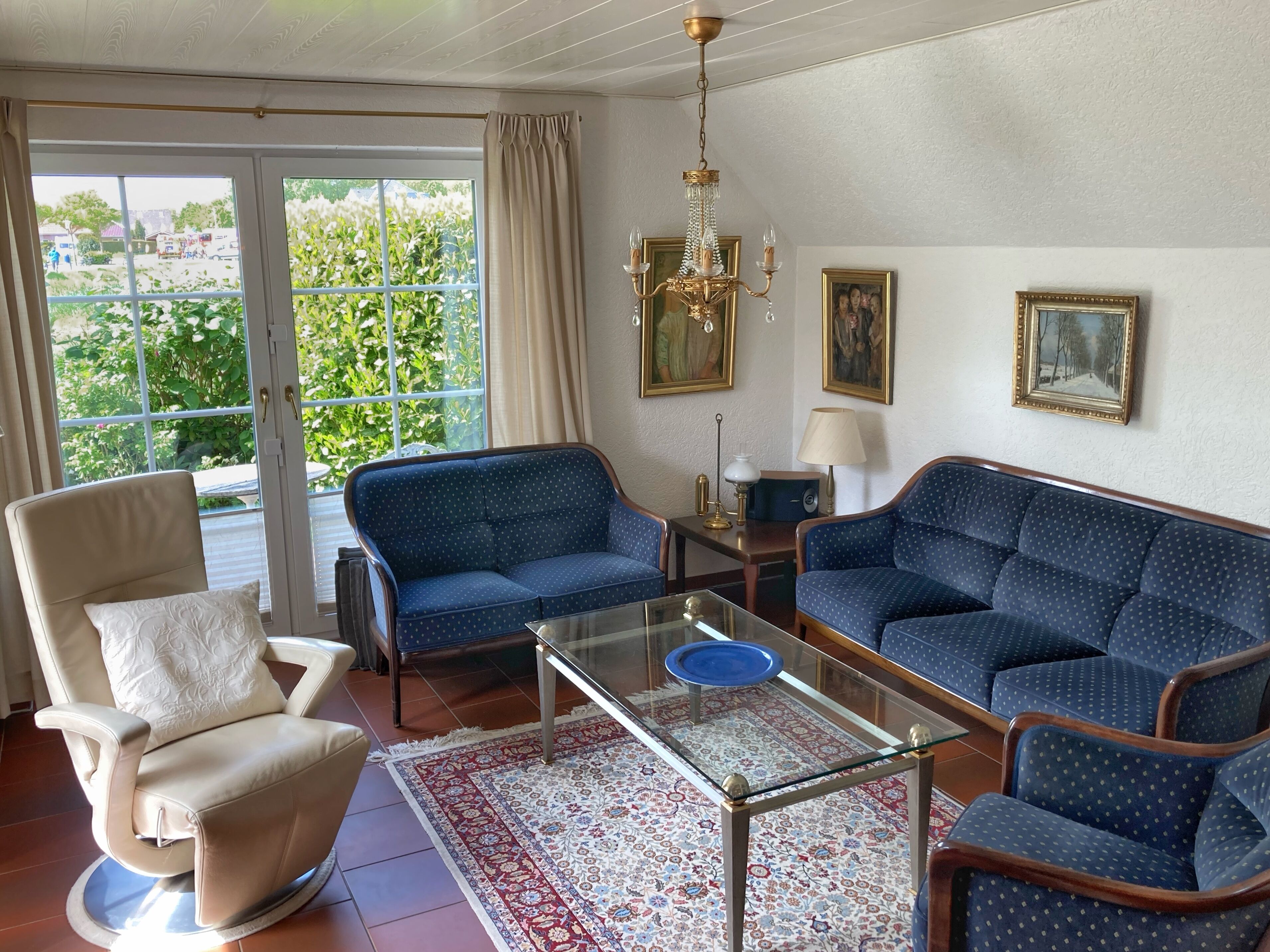 A living room with a sofa, armchair, and a glass coffee table.