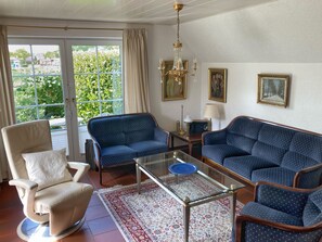 Ein Wohnzimmer mit einer Couch, einem Sessel und einem Glastisch.