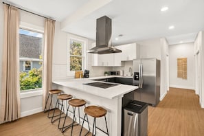 A modern kitchen with a central island, stainless steel appliances, and a view of the outdoors.