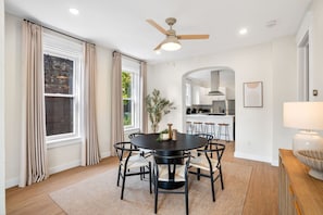 A dining area with a round table, chairs, and a ceiling fan.
