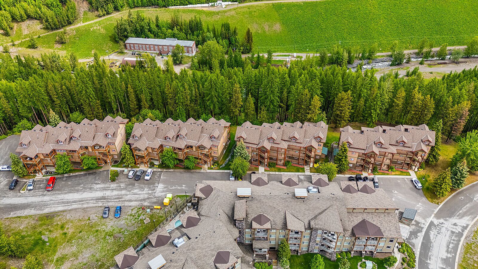 Un hôtel à plusieurs étages doté d’une cour intérieure, entouré d’une forêt dense.