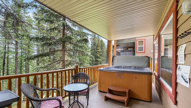 Een balkon met een jacuzzi, rieten stoelen en een tafel.
