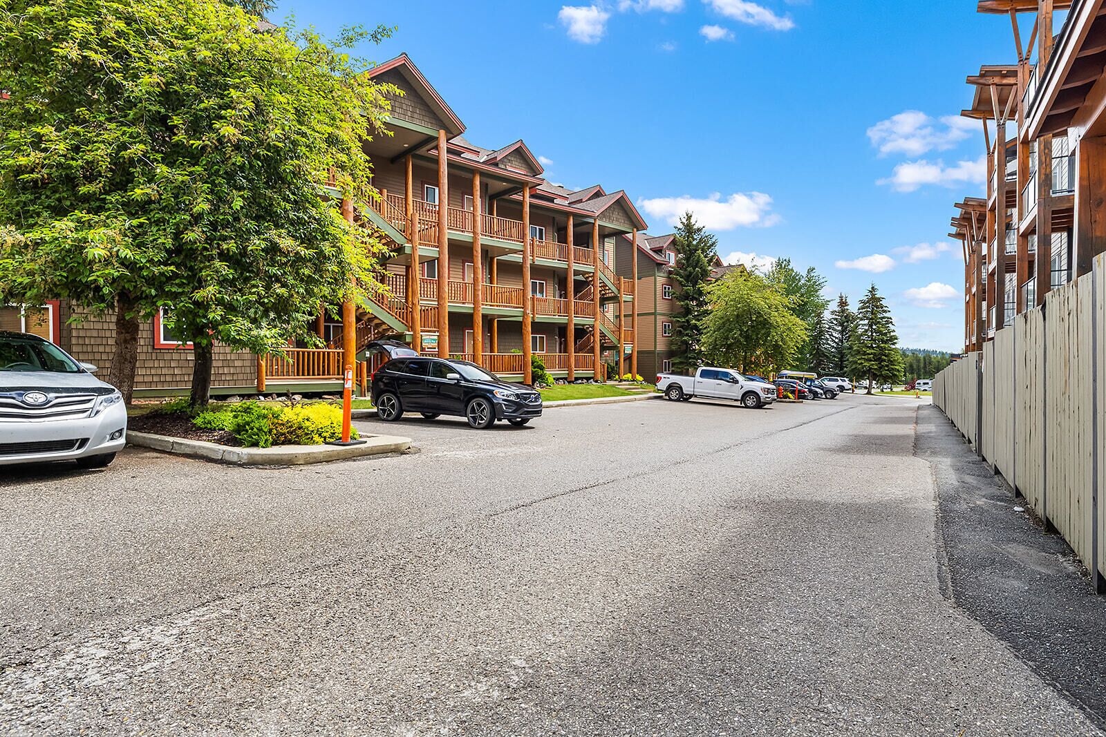 Un immeuble à plusieurs étages doté de balcons, d’un parking et surplombant un ciel dégagé.