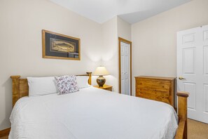 A neatly made bed with white linens, a wooden headboard, a bedside lamp, and a framed picture on the wall. - Ski-In Condo w/ Private Hot Tub - Kimberley Ridge (Kimberley)