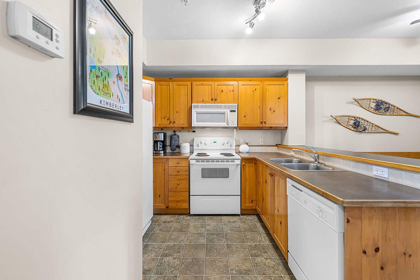 A compact kitchen with wooden cabinets, a microwave, a stove, and a dishwasher.
