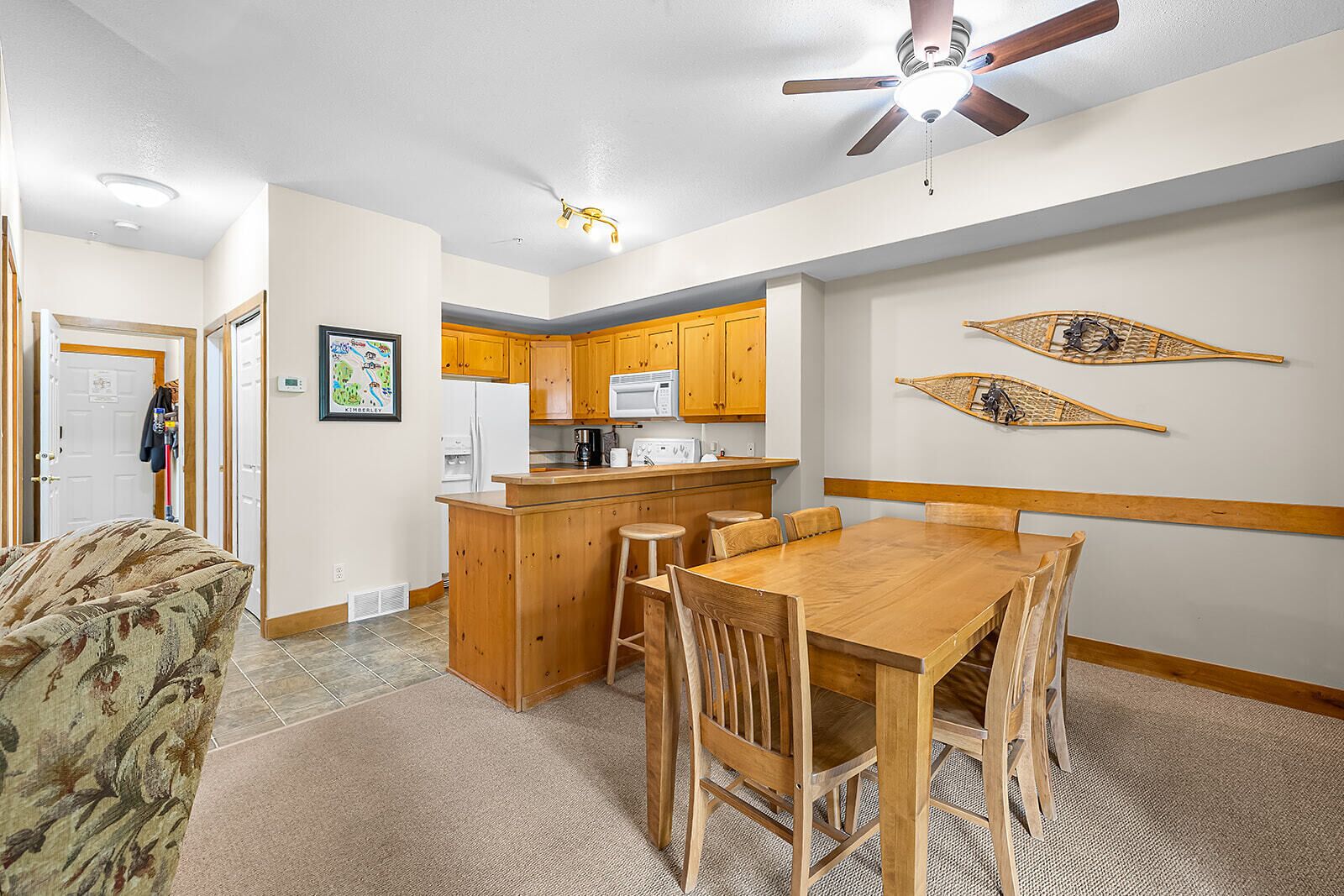 A compact kitchen with wooden cabinets, a central island, and a dining area with a wooden table and chairs.
