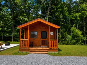 A wooden cabin with a porch, a window, and a door.