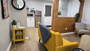 A compact living space with a yellow sofa, a small table with a remote, and a wooden accent wall.