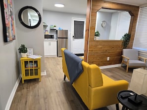 A compact living space with a yellow sofa, a small table with a remote, and a wooden accent wall.
