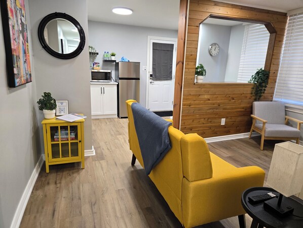 A compact living space with a yellow sofa, a small table with a remote, and a wooden accent wall.