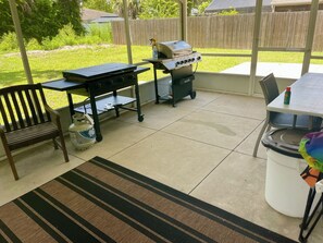 An outdoor patio area with a grill, a table, a chair, and a rug. - Coastal escape near New Smyrna Beach (Edgewater)